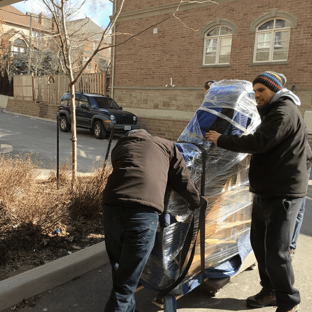 Moving crew navigating a large piece of furniture through a modern home